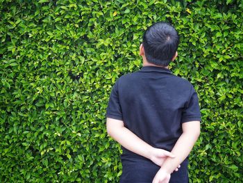 Rear view of boy standing against plants