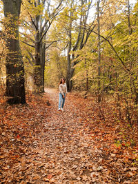 Full length of man standing amidst leaves in forest