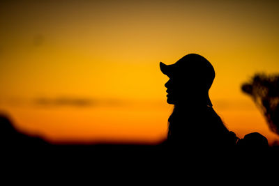Silhouette of man against orange sky