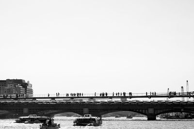 Bridge over river in city against clear sky