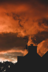 Low angle view of silhouette buildings against orange sky