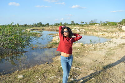 Woman wearing sunglasses standing on land against sky