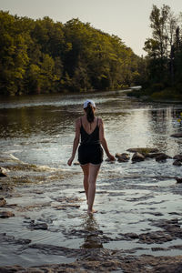 Full length rear view of woman standing on riverbank