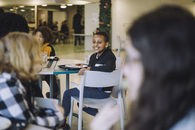 Side view of boy sitting on chair during lunch break in cafeteria at school