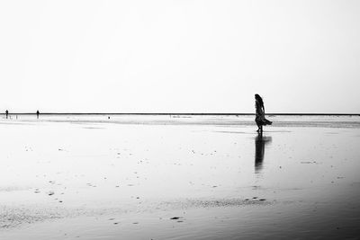 Man standing on beach against clear sky