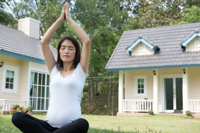 Pregnant young woman meditating while sitting on grass