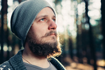 Thoughtful man wearing knit hat in forest