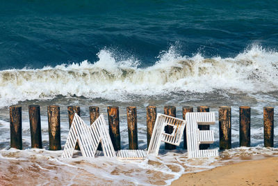 Large wooden letters forming inscription sea in russian against background of baltic sea