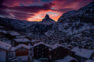 Snow covered townscape against mountain during sunset