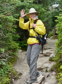 Full length portrait of a smiling young woman standing against plants