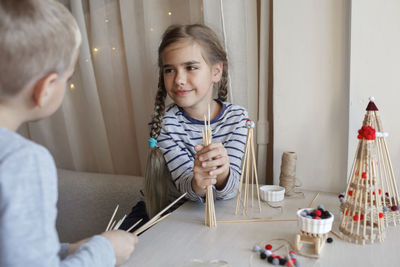 Cute sibling playing with christmas ornaments at home