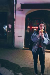 Full length of man standing on footpath at night