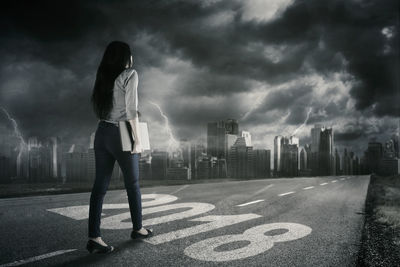 Rear view of businesswoman walking on road in city