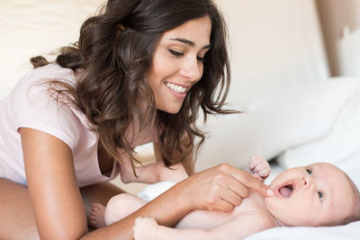 Smiling mother playing with cute daughter on bed
