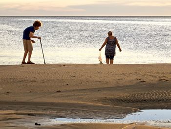 Full length of friends standing on beach