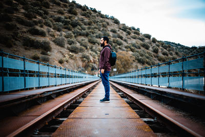 Rear view of man standing on railroad track