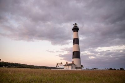 Lighthouse on field against sky during sunset