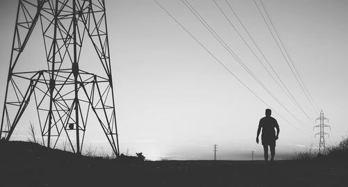 Silhouette of electricity pylon against clear sky