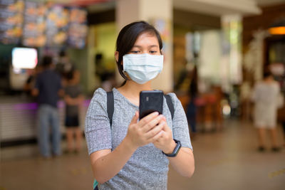 Woman with mask using phone outdoors