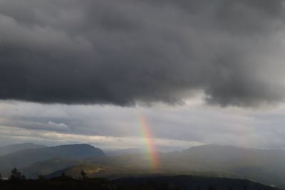 Rainbow over mountain against cloudy sky