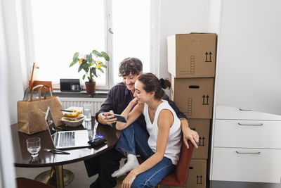 Couple sitting at table and using smart phone