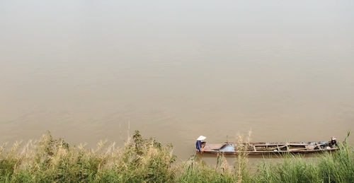 Fishermen take a wooden boat to find fish by the mekong river.