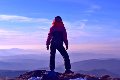 Full length of woman standing on mountain against sky during sunset