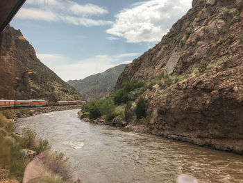 Scenic view of river by mountains against sky