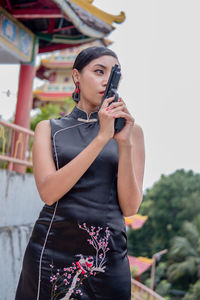 Young woman drinking water while standing outdoors