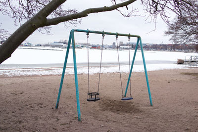 Empty swing in park against sky