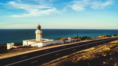 Lighthouse by sea against sky