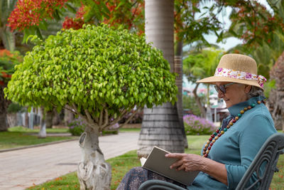 Side view of senior woman sitting on bench at park