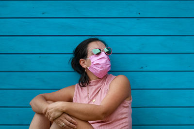 Portrait of woman sitting against blue wall