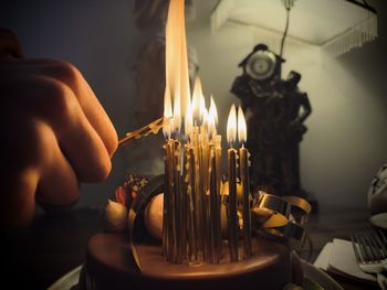 Cropped hand of woman holding lit candle