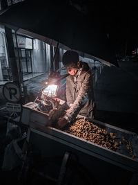 Rear view of man holding illuminated lanterns at night