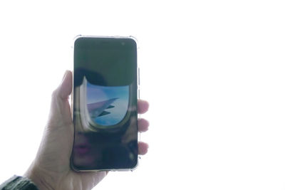 Close-up of hand holding smart phone against white background