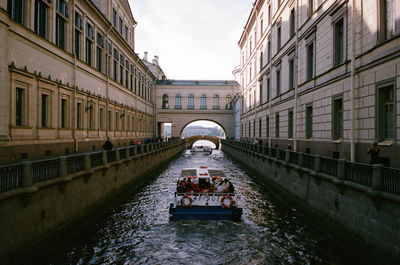 People in canal in city against sky