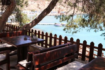 Chairs and table by lake against trees
