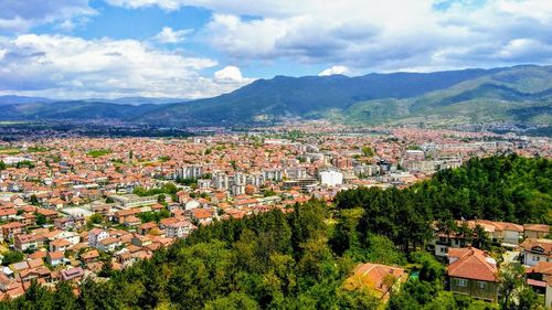 Aerial view of townscape and mountains against sky