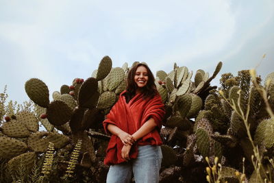 Portrait of smiling young woman standing against sky