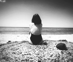 Rear view of woman standing at beach against clear sky