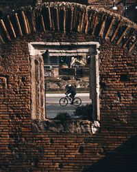Man and bicycle against brick wall of building