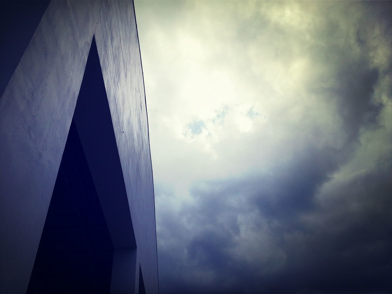 low angle view, sky, cloud - sky, cloudy, architecture, built structure, cloud, weather, building exterior, overcast, no people, outdoors, high section, cloudscape, day, dusk, nature, directly below, part of, building