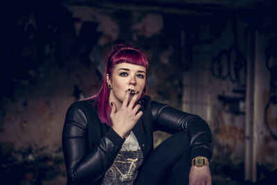 Portrait of young woman smoking cigarette in abandoned building