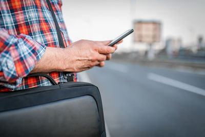 Close-up view of businessman with sunglasses and plaid shirt who  walking and typing messages 