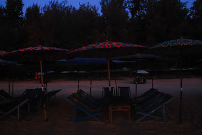 Chairs and tables on beach against trees