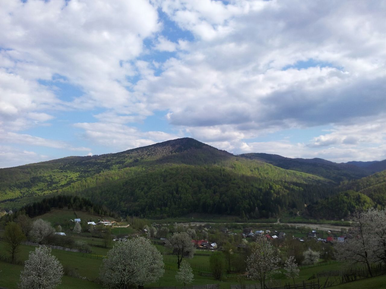 mountain, sky, cloud - sky, scenics, tranquil scene, tree, mountain range, beauty in nature, tranquility, cloudy, landscape, nature, cloud, green color, growth, idyllic, non-urban scene, high angle view, day, hill