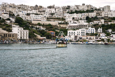 Sailboats in sea by buildings in city