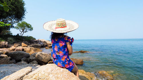 Woman wearing hat against sea against clear sky