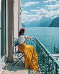 Rear view of woman sitting on railing